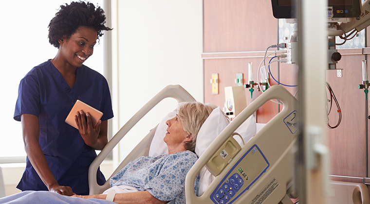 Speech Therapist With Digital Tablet Talks To Senior Patient